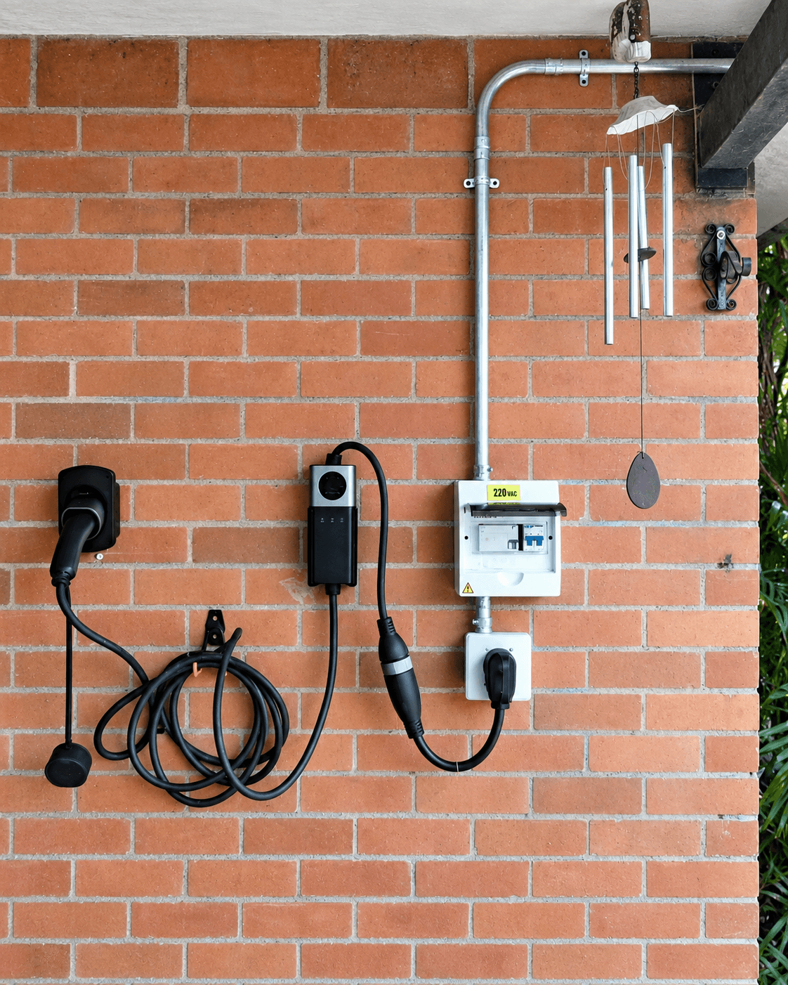 Equipos de carga, cables, tablero eléctrico y canalización sobre una pared de ladrillo