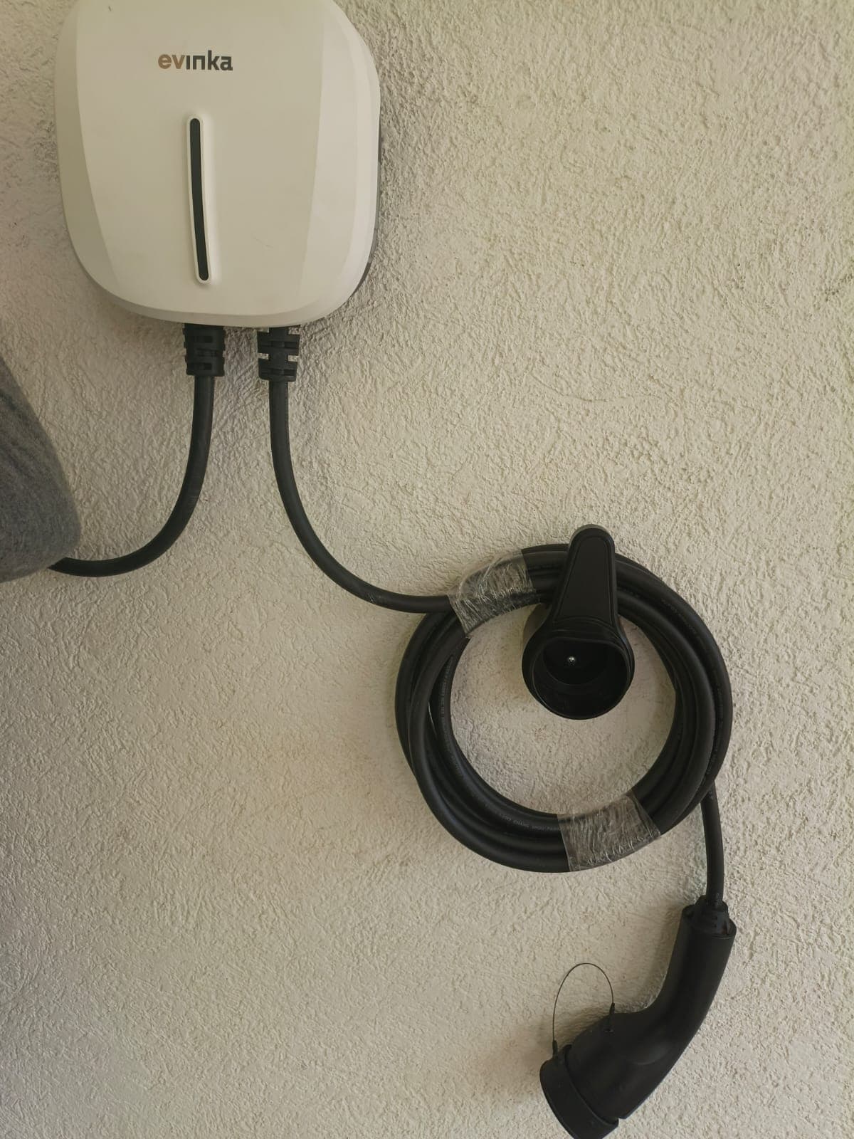 Cargador blanco fijado a una pared con cable enrollado y conector en su soporte